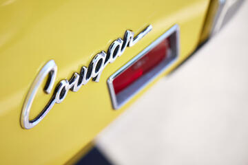 close up of Cougar car logo on yellow Mustang