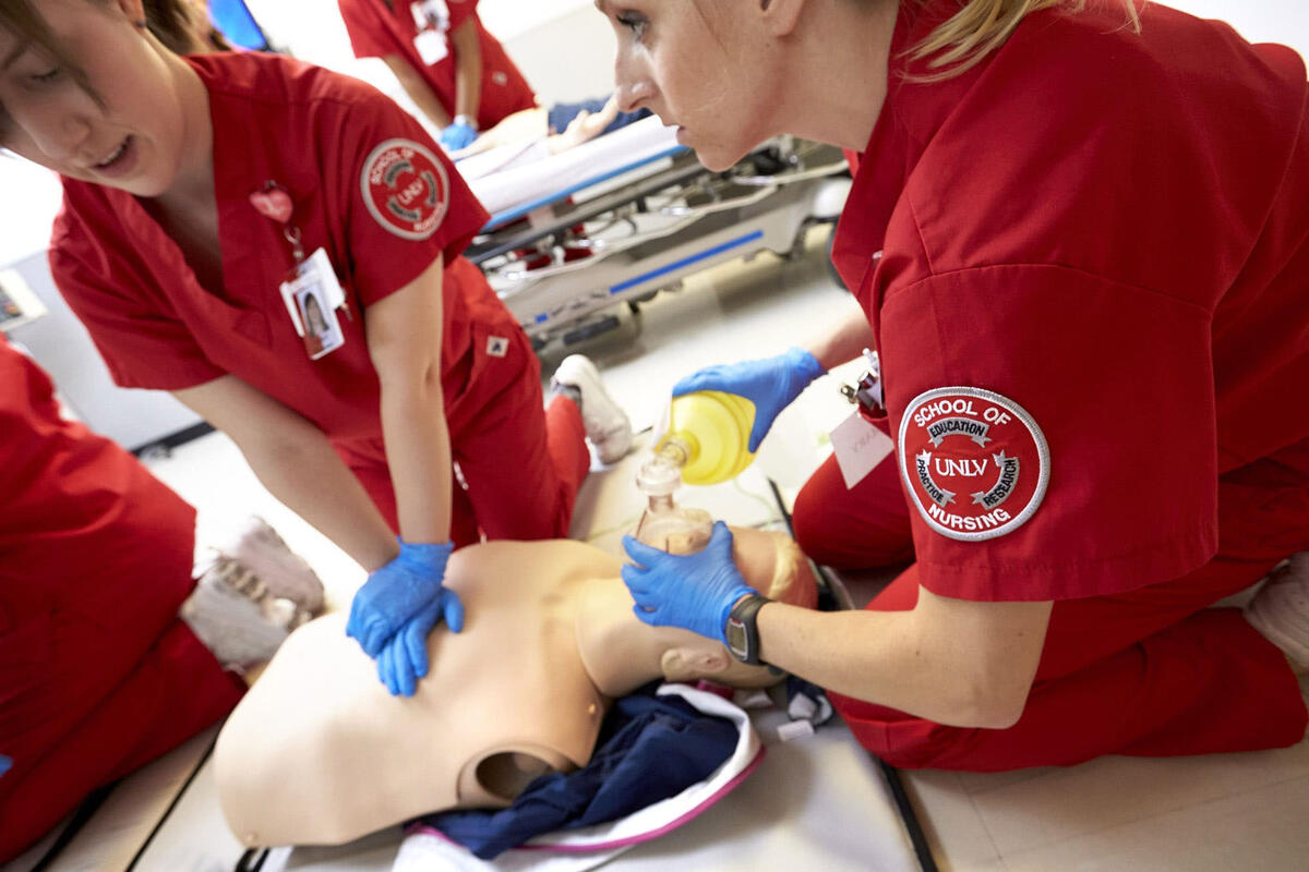 Nursing students performing CPR on a training dummy.
