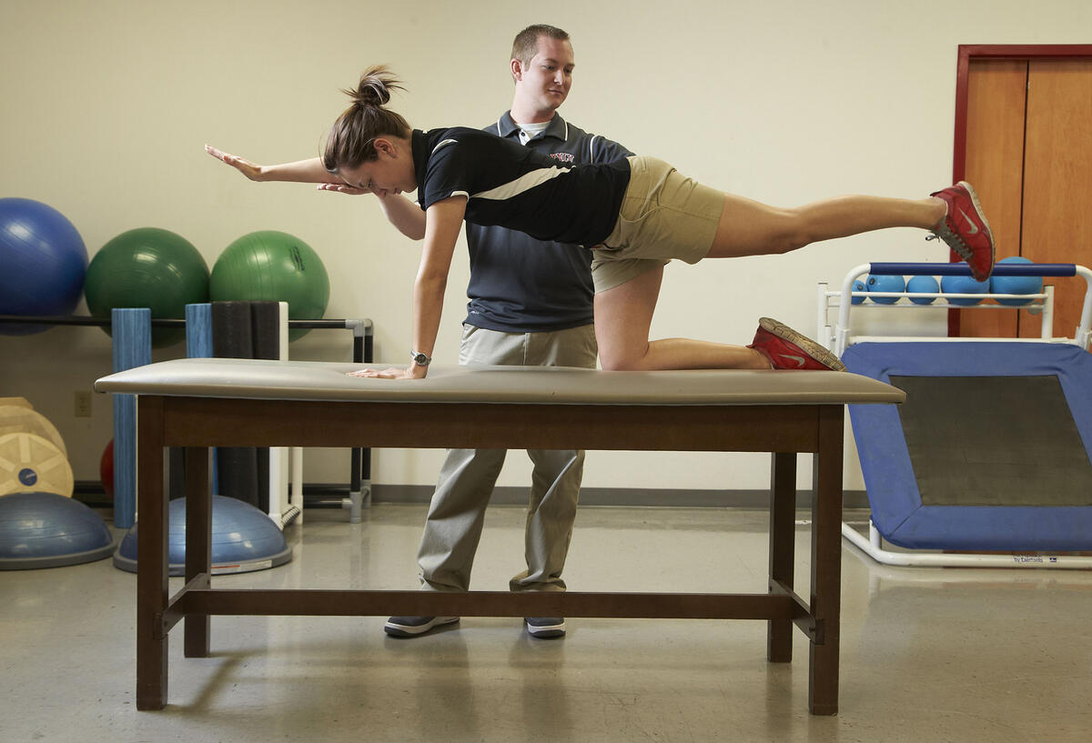 Athletic trainer helps woman with her form