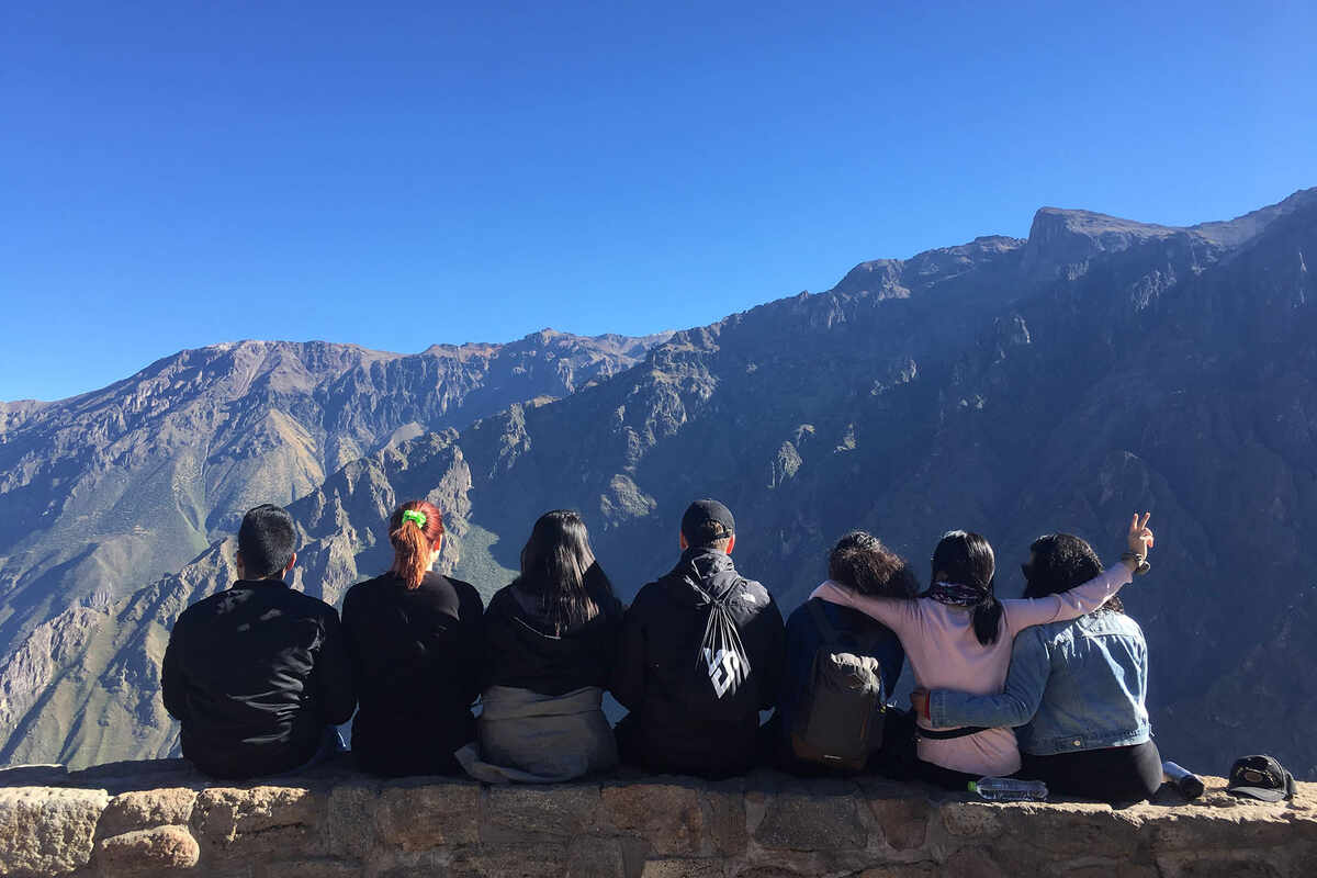 Group of people sitting away from the camera looking at mountain range