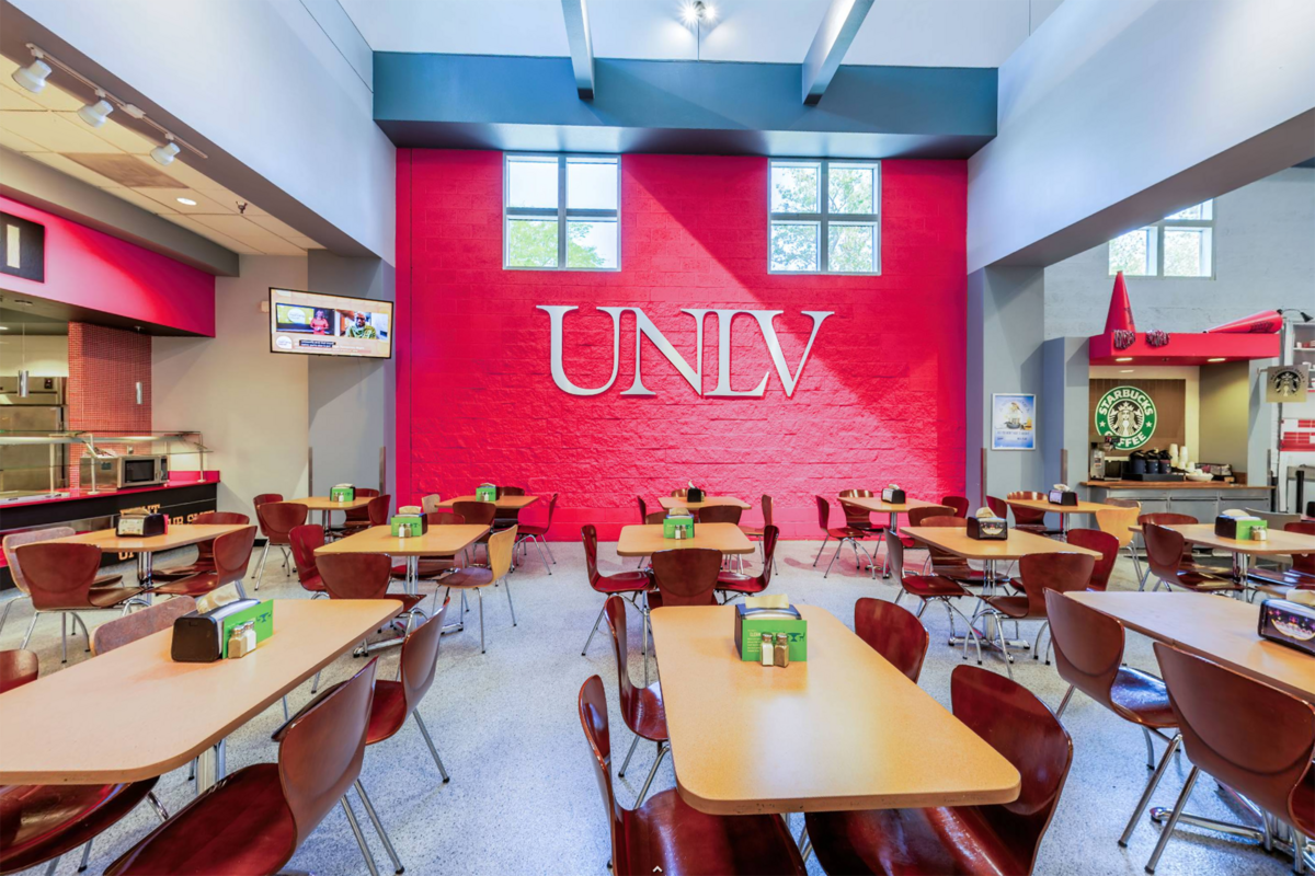 Medium-sized landscape view of a UNLV dining area with a square red wall in the background with the UNLV logo on it