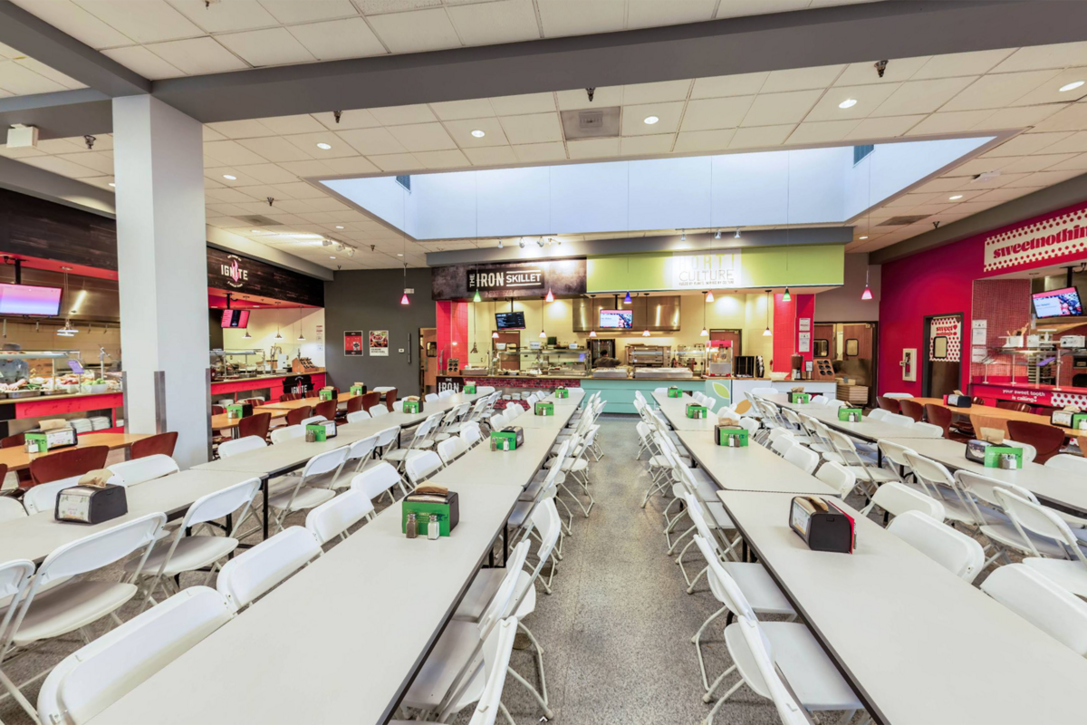 A view of a cafeteria area with different restaurants and numerous tables and chairs