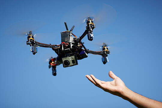 Hand reaching toward a drone in flight