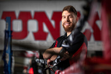 A student poses in a boxing ring with &quot;UNLV&quot; letters drawn on the wall behind him.