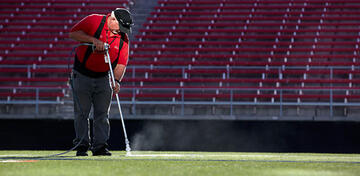 Worker repainting the lines of the Sam Boyd Stadium football field.