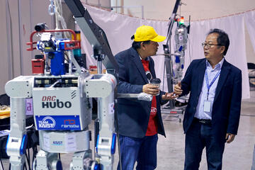 UNLV professor Paul Oh, left, talks with his cousin, JunHo Oh of the South Korean Team Kaist, the eventual winner of the DARPA Robotics Challenge finals.