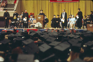 The commencement dais is seen over a sea of mortarboards