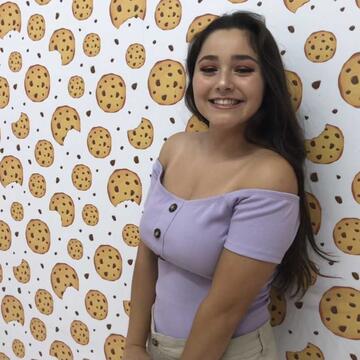 Student in front of a wall with cookie wallpaper (Ruby Valencia)