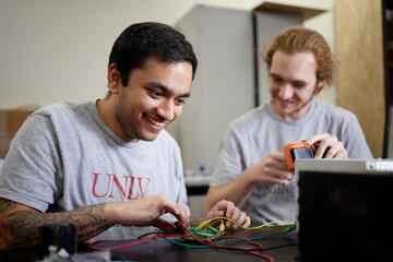 Akshay Dave (left) and Nicolas Kosanovic make final preparations for the XPRIZE competition. (Josh Hawkins)