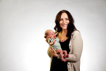 woman holding a newborn baby to chest while smiling at camera