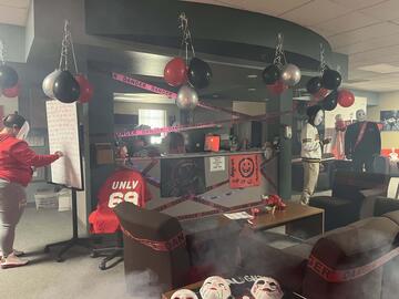 An office decorated in red, black, and gray balloons with yellow "Caution" tape placed on desks and walls.