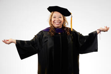 woman in black graduation gown and cap in front of white background