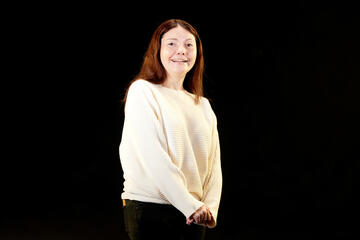 female student in white long-sleeve sweater in front of black background
