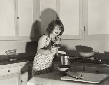 black and white photo of clara bow cooking in the kitchen