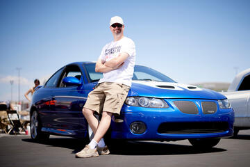 man leaning against blue car