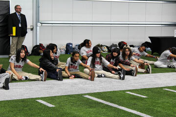 group of female students stretching on sideline