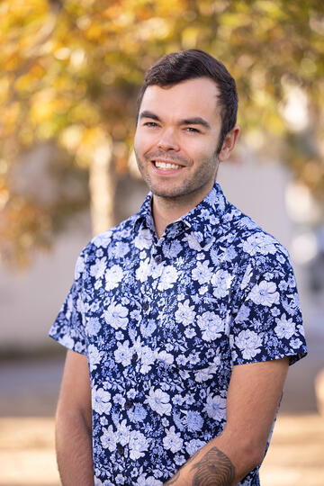 cropped photo of man standing and wearing graphic blue and white print shirt