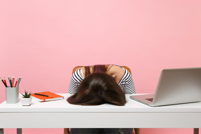 A woman's head is face-down on a desk in frustration