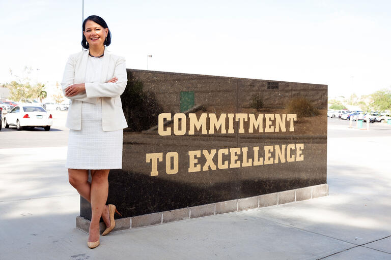 woman posing by sign saying &quot;commitment to excellence&quot;