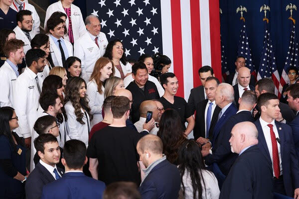 president greeting large group of healthcare students with U.S. flag in background