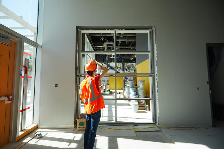 Construction worker assessing a window panel inside the UNLV Advanced Engineering Building.