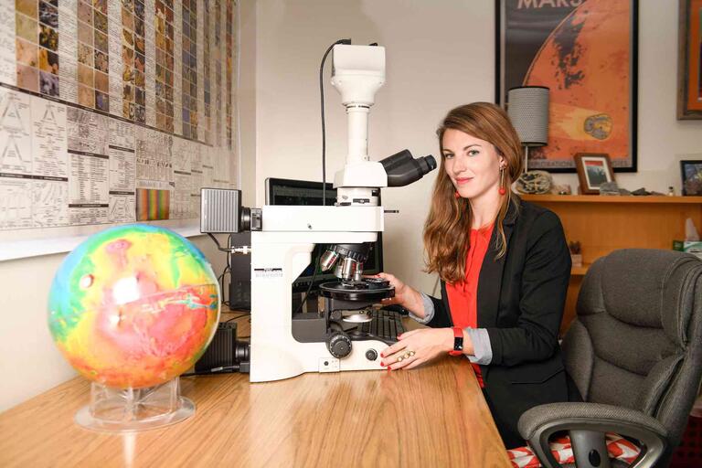 U.N.L.V. geoscientist Arya Udry sits in front of her microscope in her office