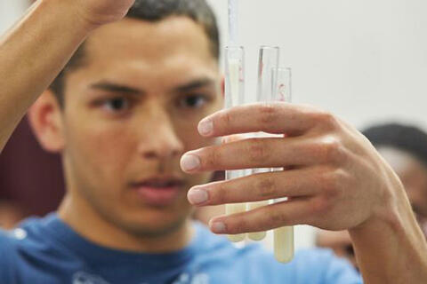 Male student working with beakers.