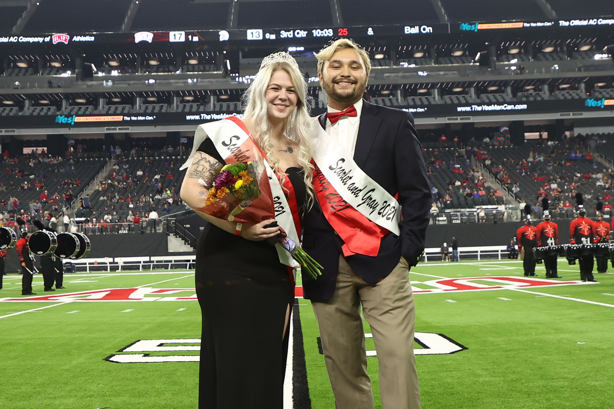 man and woman on football field in formal clothing