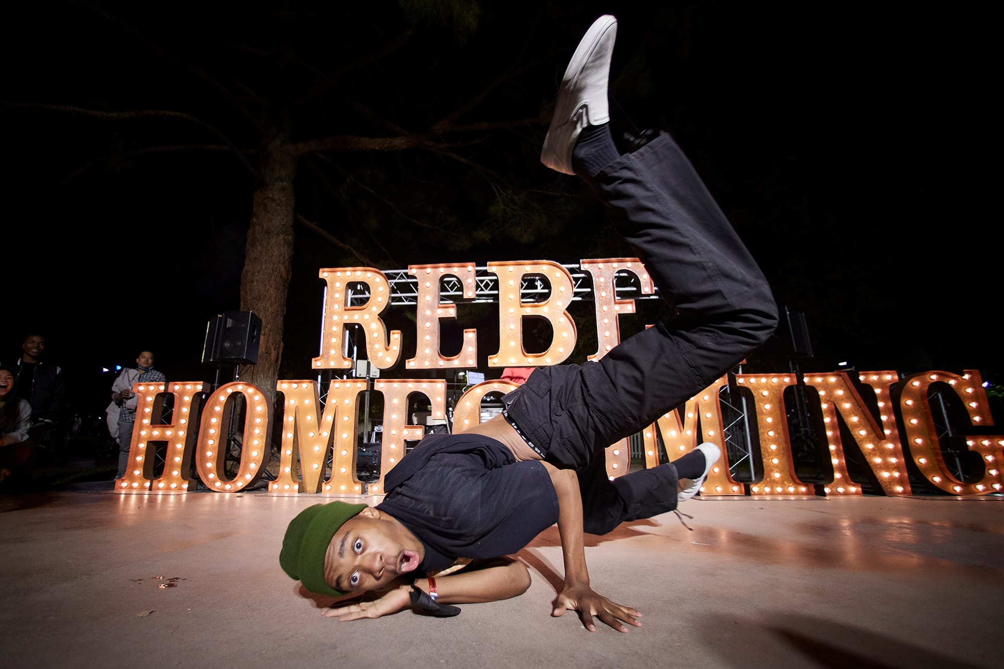 Student breakdancing in front of Rebel Homecoming sign