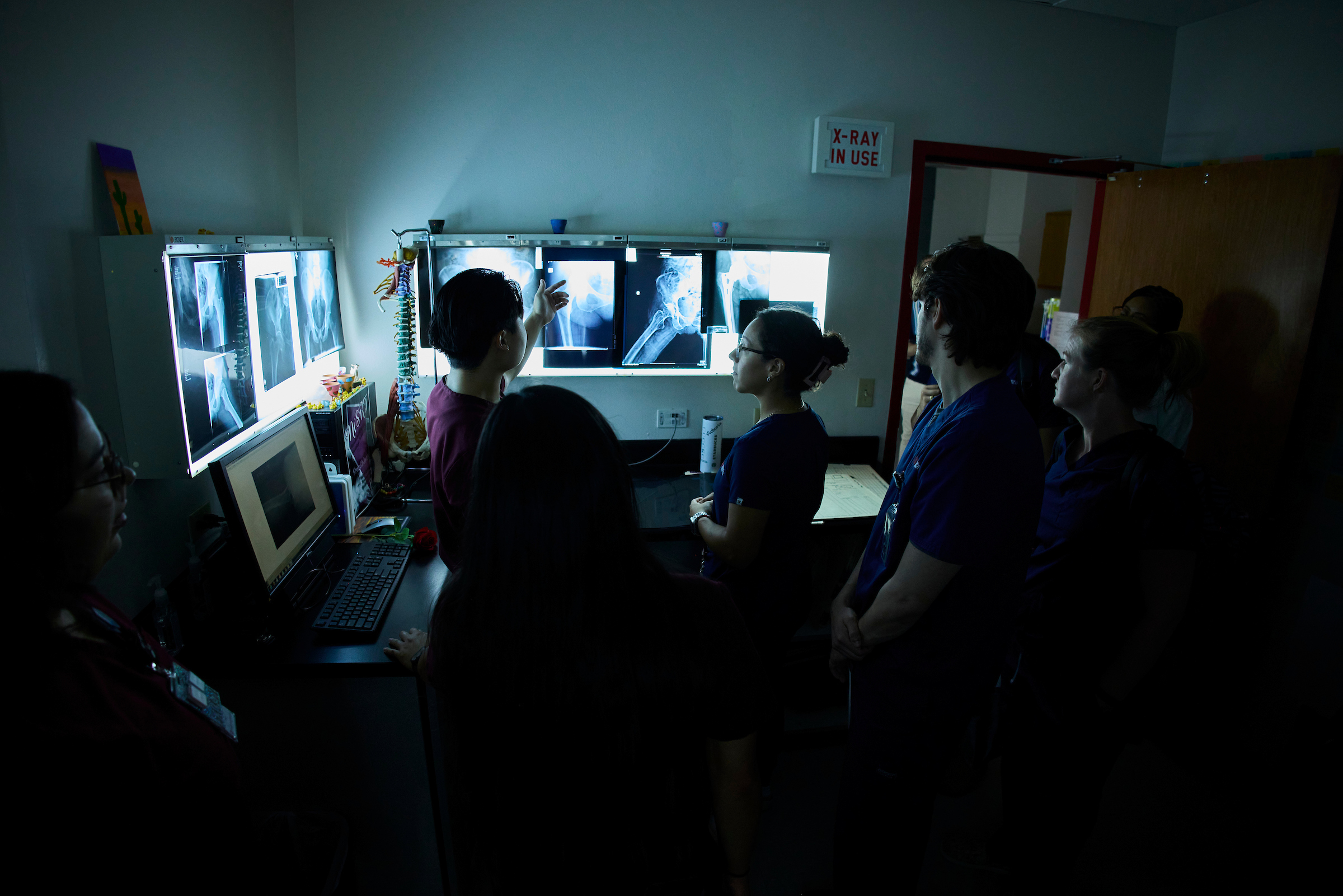 Radiography and physical therapy students observing x-rays in a dark room.