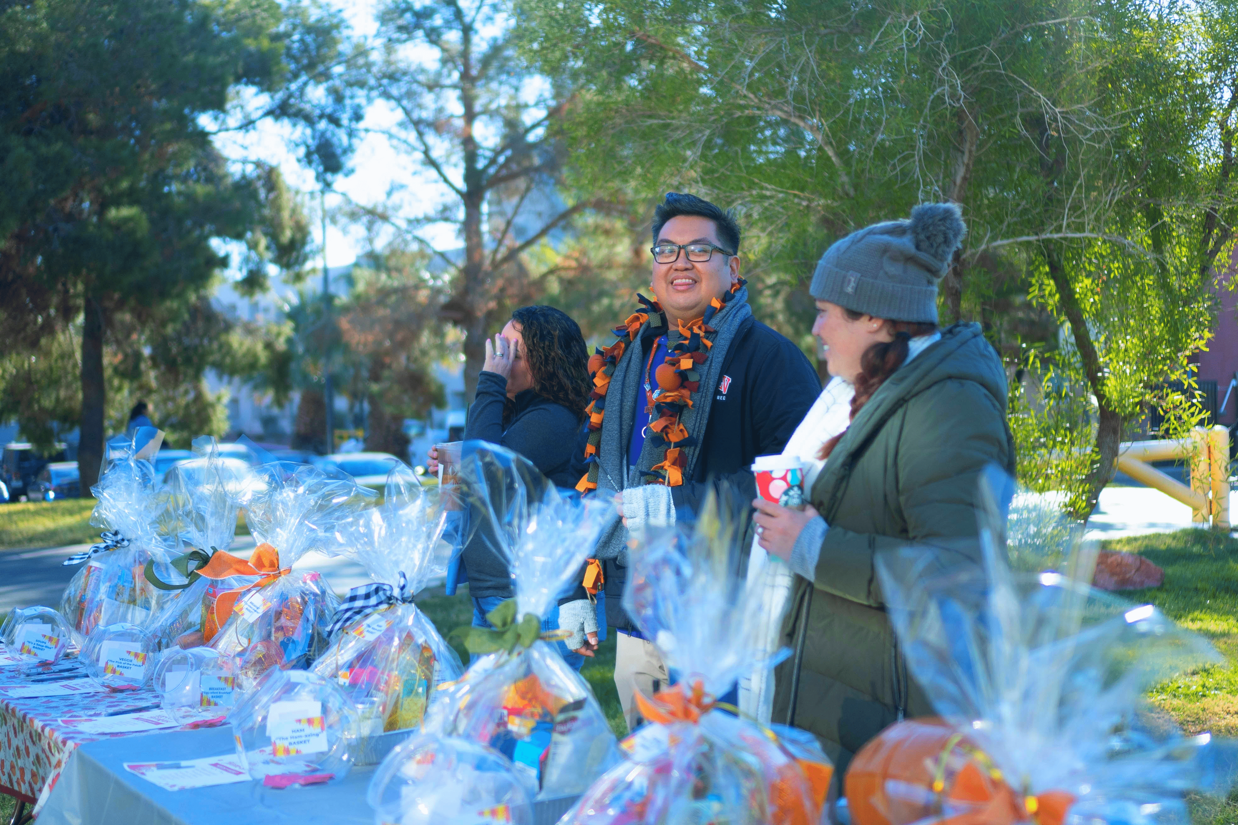 Three people standing by a table with gift baskets