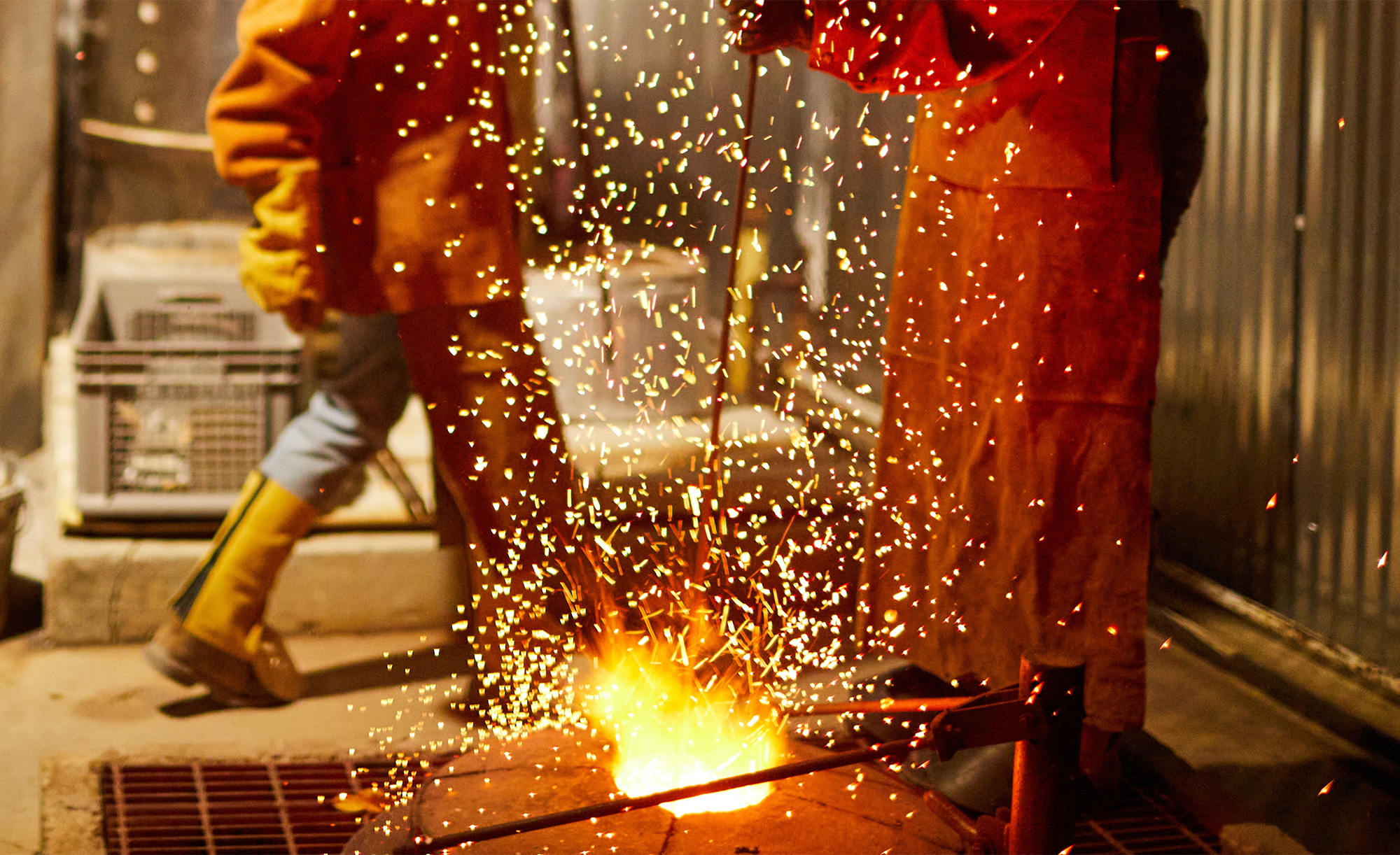 Two people standing over a fire pit
