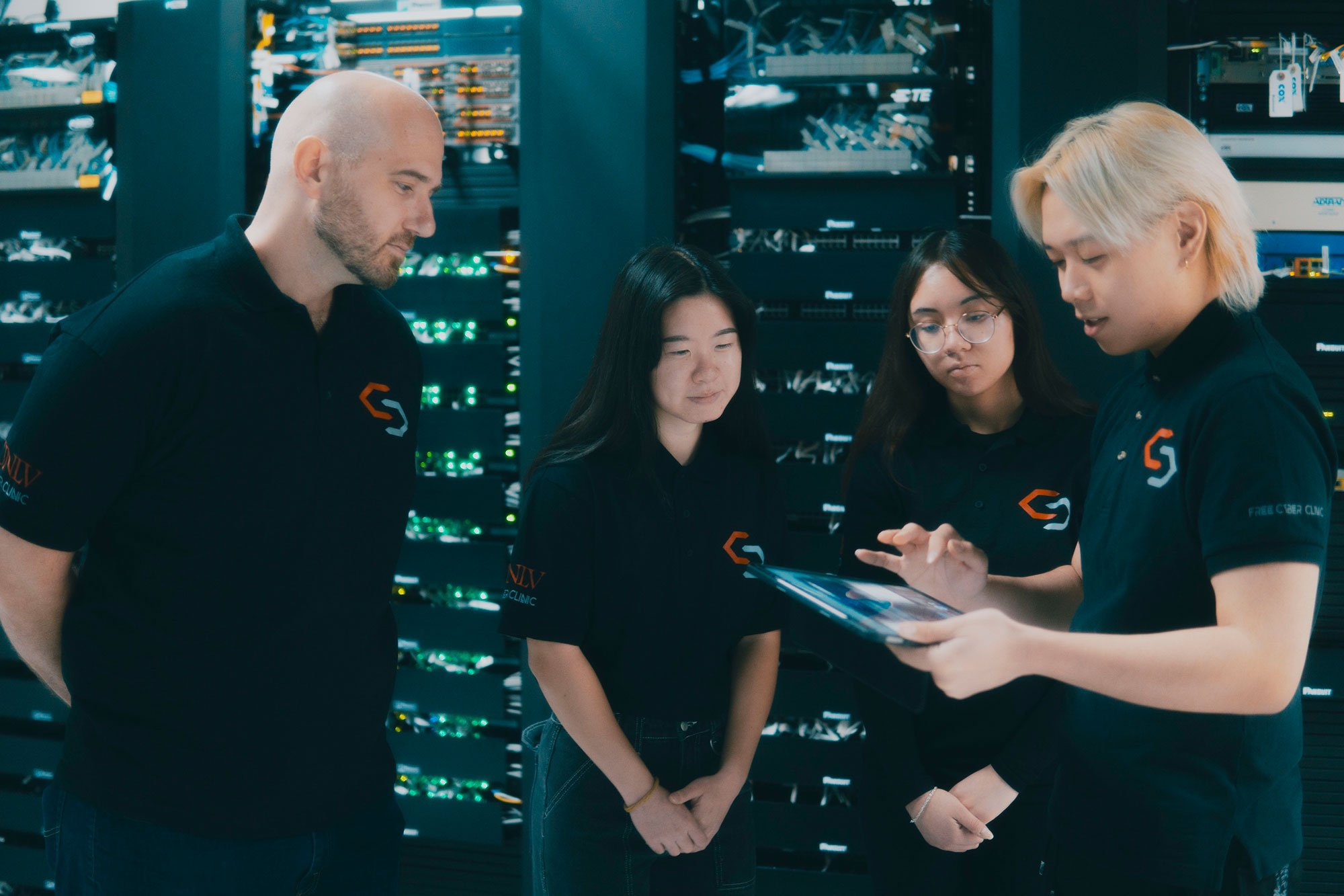 Students looking at a tablet together in a server room.