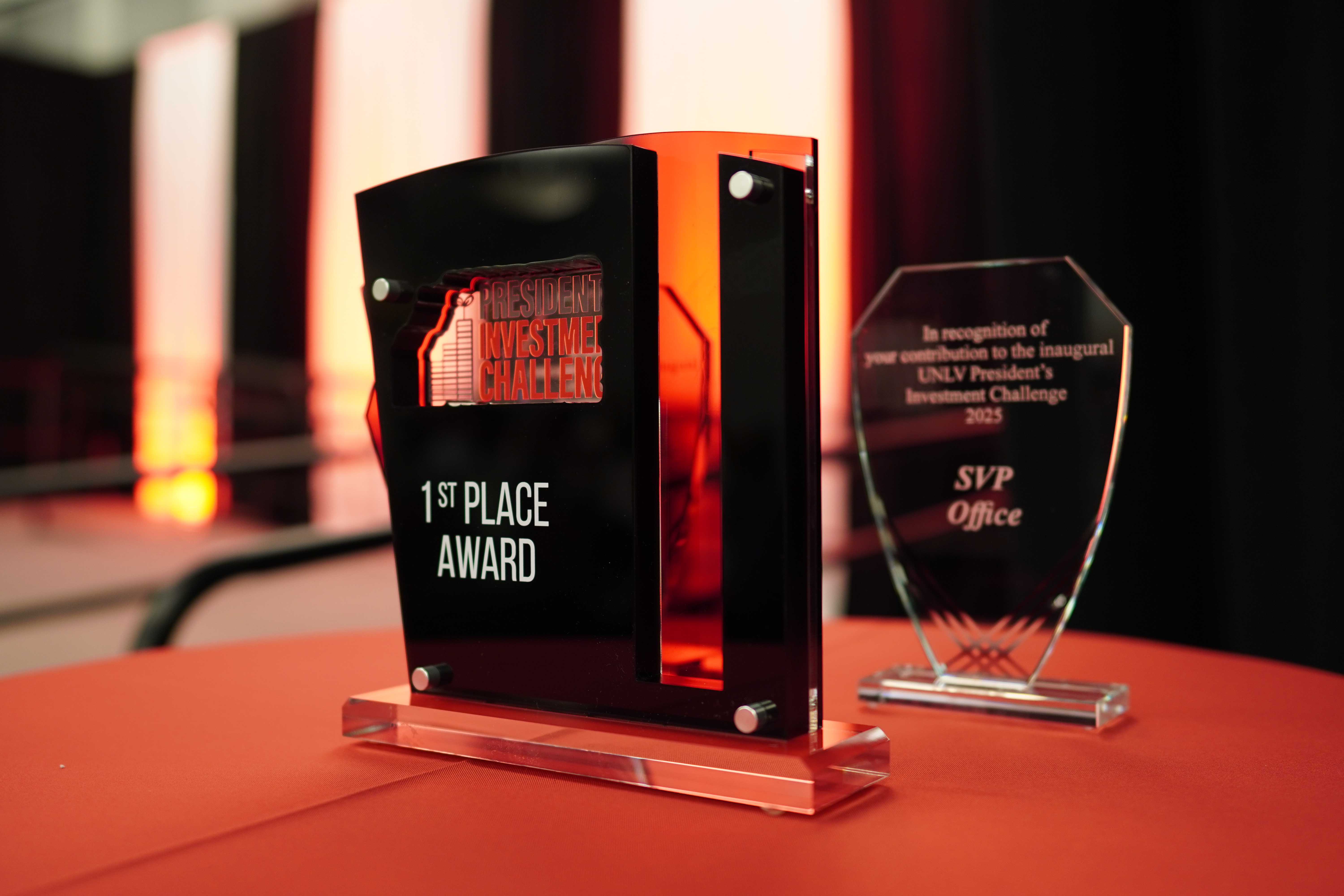 A trophy that says "President Investment Challenge 1st Place Reward" with a reward behind it labeled "SVP Office"