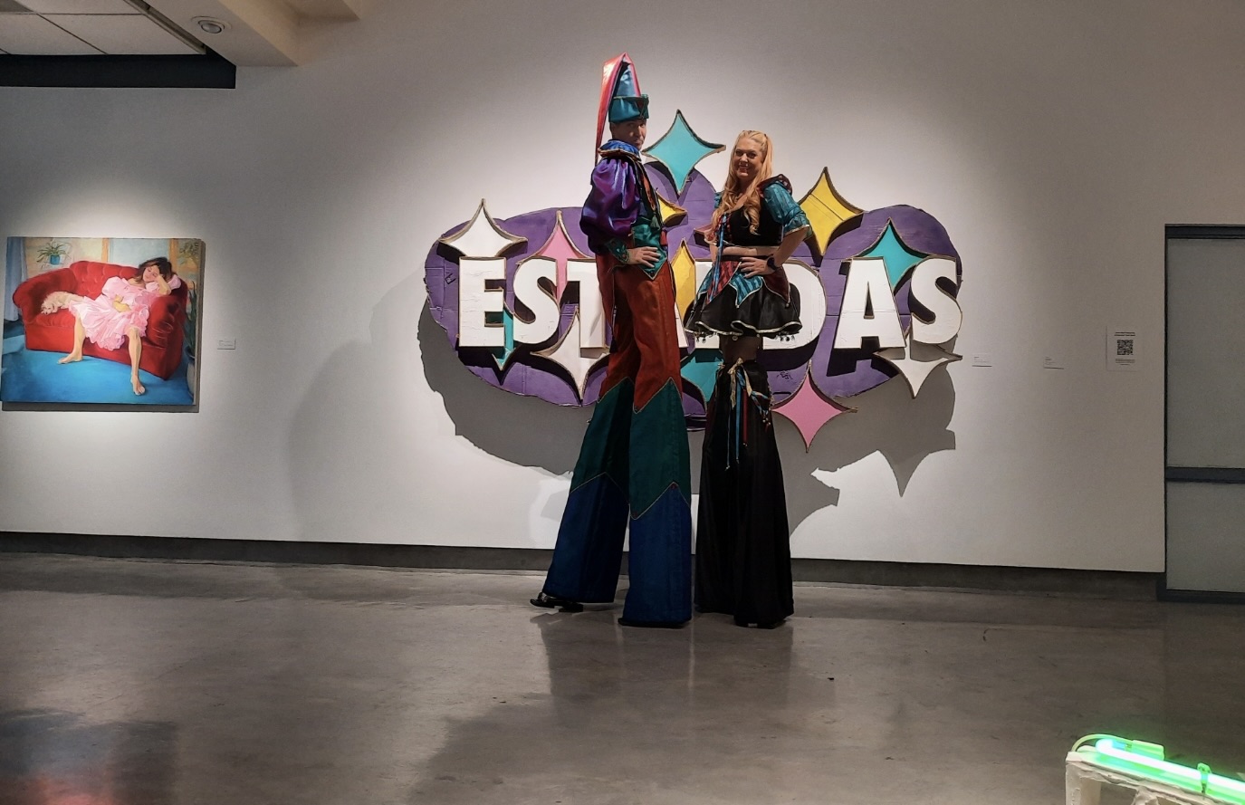 2 people on platforms in costume posing in front of a sign