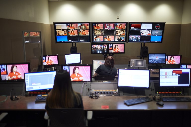 People sitting at desks with multiple screens