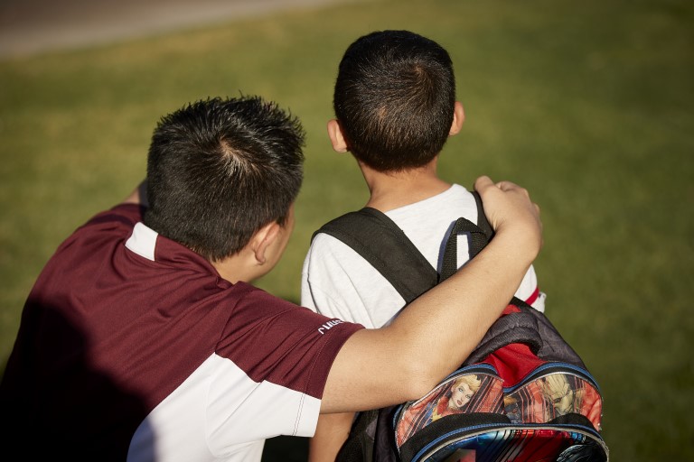 Man with arm around kid with backpack