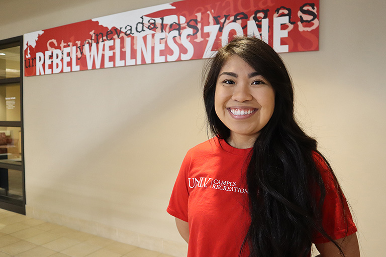 A woman standing in front of the Rebel Wellness Zone
