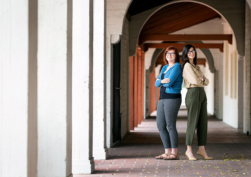 Two women standing with their backs against each other