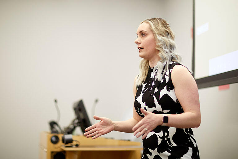 A woman speaking in front of a classroom.