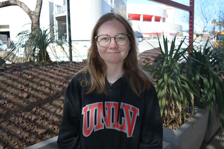 A woman wearing glasses and a UNLV hoodie smiling.