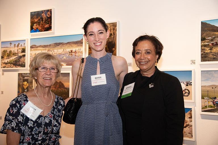 Three women standing together with arms behind them.