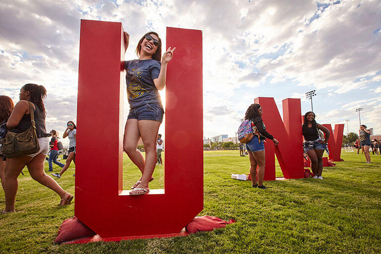 People walking around a U-N-L-V sign