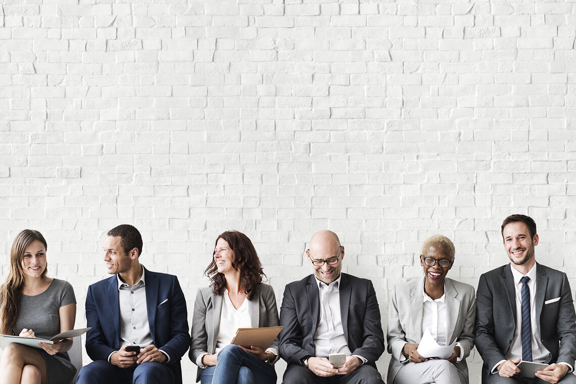 A row of people sitting down in business attire.