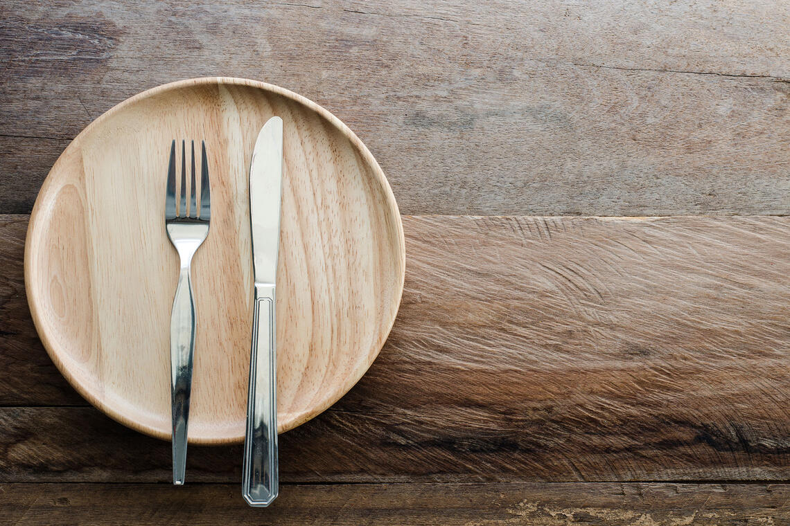 Close up shot of a wooden plate, a silver fork and knife