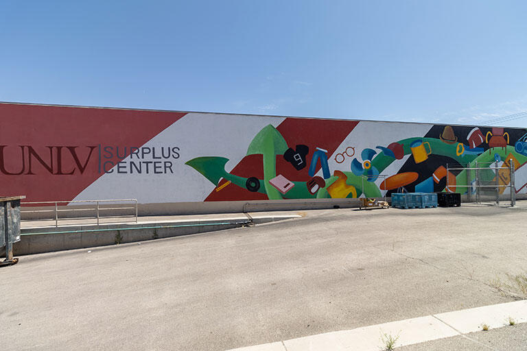 A painting on the side of the Surplus Building of recycled and surplus goods.