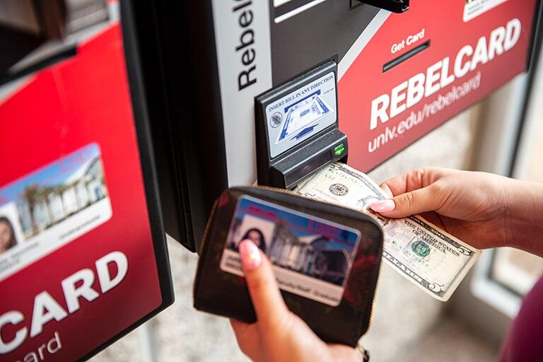 Person inserts cash into Rebel Card machine