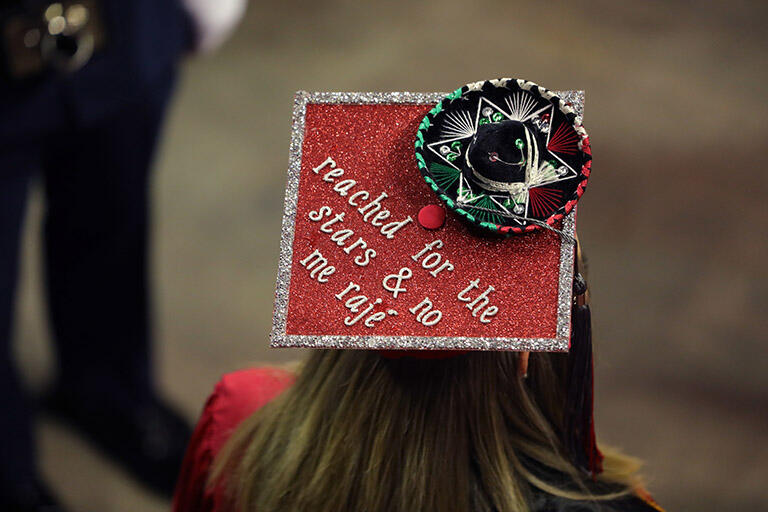 Una gorra de graduación decorada con un pequeño sombrero verde, blanco y rojo, y con una cita que dice "reached for the stars and no me rajé."