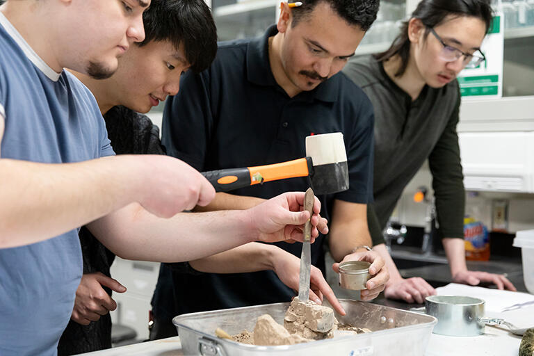 Group of students working on rocks with various tools