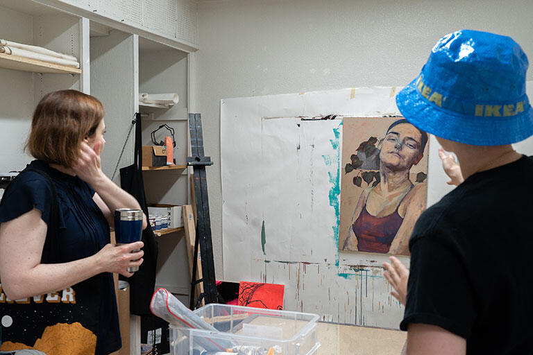 Two people looking at an artwork of a portrait